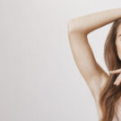 Young woman showing smile, in white casual smart clothing, on grey background, with copyspace area for advertisiment, text or slogan. Advertising concept. Horizontal banner composition.