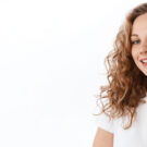 Young woman showing smile, in white casual smart clothing, on grey background, with copyspace area for advertisiment, text or slogan. Advertising concept. Horizontal banner composition.