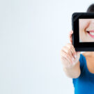 Young woman showing smile, in white casual smart clothing, on grey background, with copyspace area for advertisiment, text or slogan. Advertising concept. Horizontal banner composition.